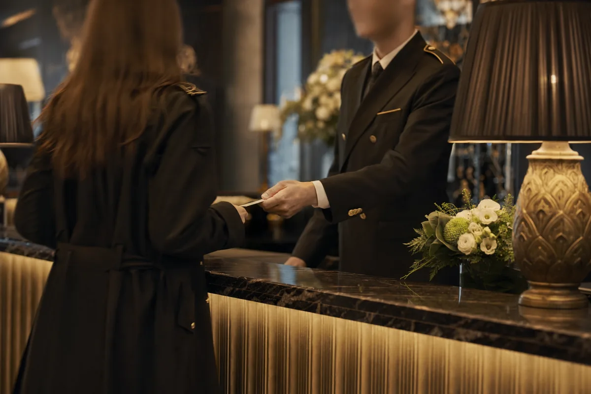 Concierge de palace accueillant un client dans un lobby luxueux