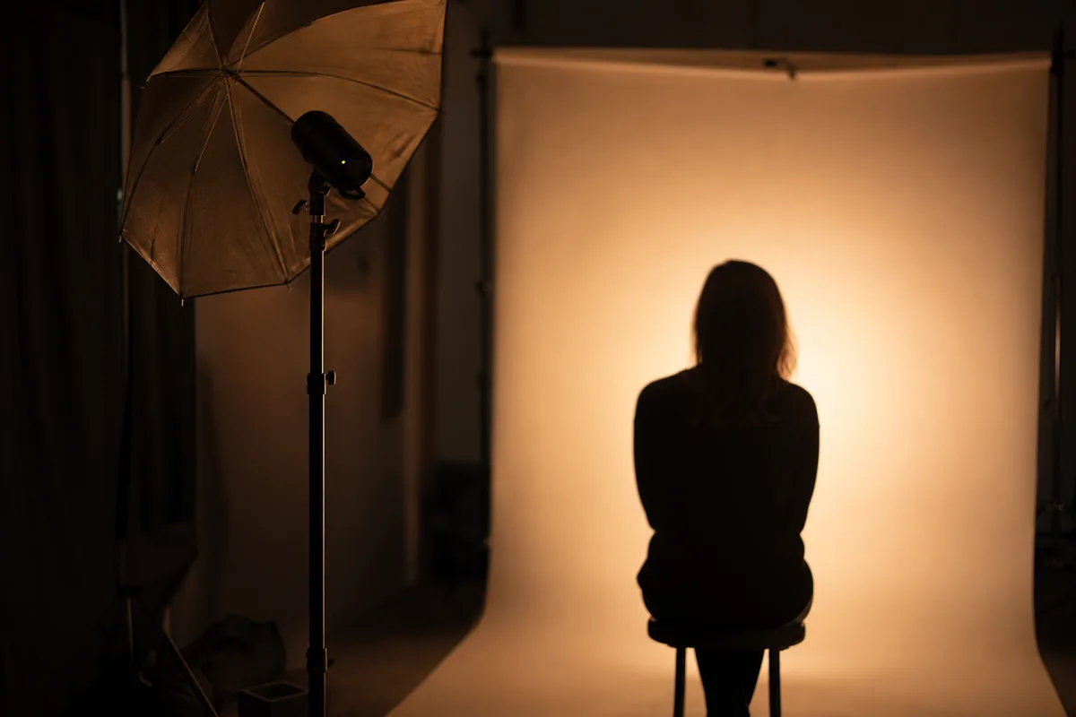 Séance photo en studio, éclairage en contre-jour sur fond neutre, silhouette hors champ