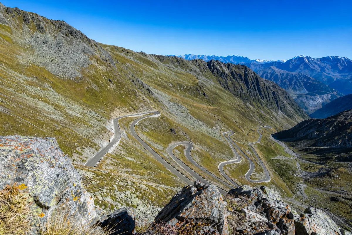 Épingles routières d’un col alpin vues en plongée depuis un promontoire rocheux